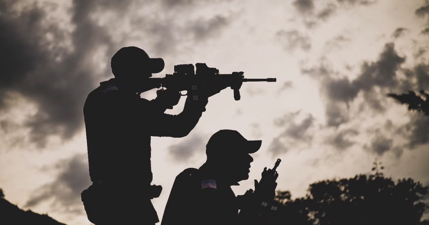 Policiais militares do Espírito Santo em ação — silhueta com armamento contra céu dramático